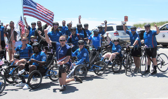 Warriors gather for a group photo during Soldier Ride, cheering at the camera while sitting on bicycles and adaptive bikes.