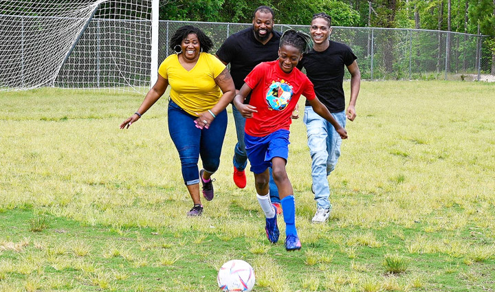 Wounded warrior Taniki Richard, her husband, and her sons play soccer on a soccer field.