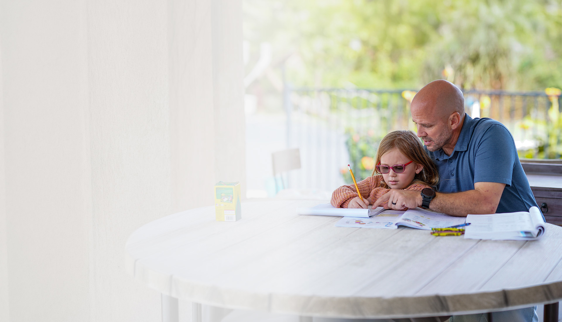 Warrior Dan Nevins sits with a child, working together on an activity and focusing on the open workbook in front of them.