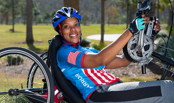 Wounded warrior Sharona Young, dressed in her WWP riding gear, proudly sitting on her custom-made bike, smiling at the camera.