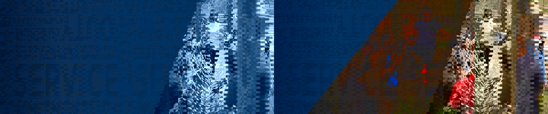 A female warrior participates in a ropes course while being cheered on by her peers