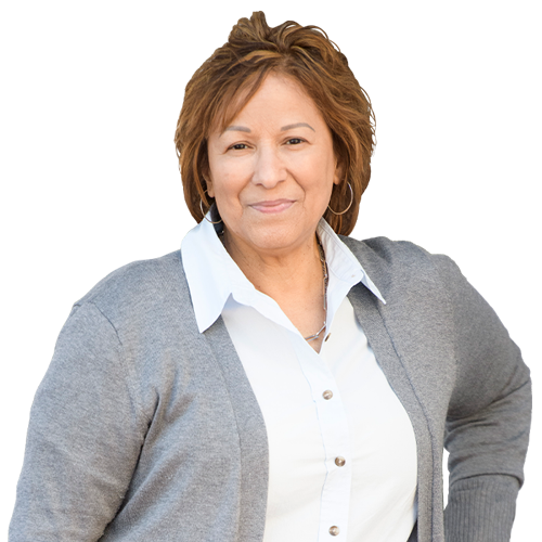 Caregiver Cindy Parsons looks at the camera while posing proudly. She wears a white shirt and a gray cardigan.