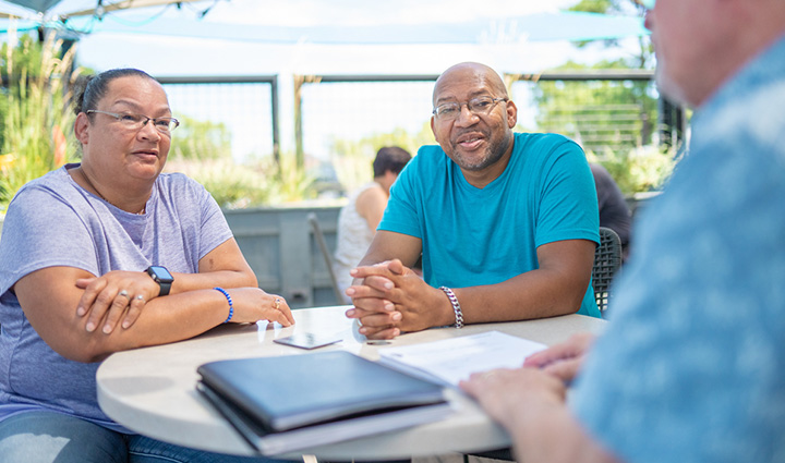 Warrior Richard Daniel and his wife, Mina, sit at a table together to speak with a financial planner.